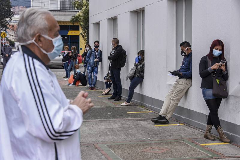 People wearing protective masks keep their distance they queue to enter a medical clinic on March 30, 2020 in Bogota, Colombia. Colombia started a national quarantine on March 25 until April 13 to control spread of COVID-19. The pandemic has spread to many countries across the world, claiming over 20,000 lives and infecting hundreds of thousands more