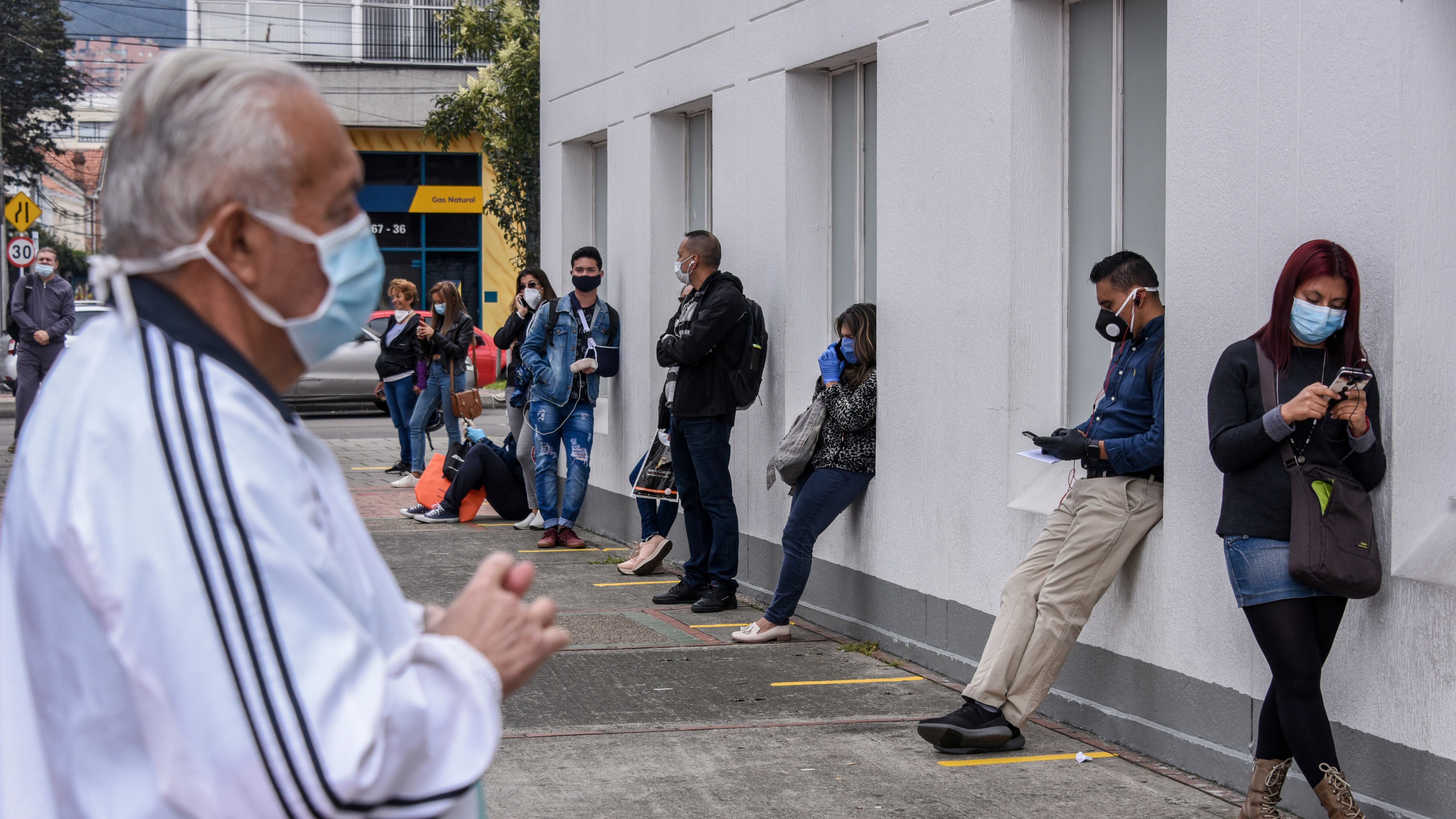 People wearing protective masks keep their distance they queue to enter a medical clinic on March 30, 2020 in Bogota, Colombia. Colombia started a national quarantine on March 25 until April 13 to control spread of COVID-19. The pandemic has spread to many countries across the world, claiming over 20,000 lives and infecting hundreds of thousands more