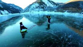 ​Padre e hijo patinan sobre una represa congelada en Estados Unidos